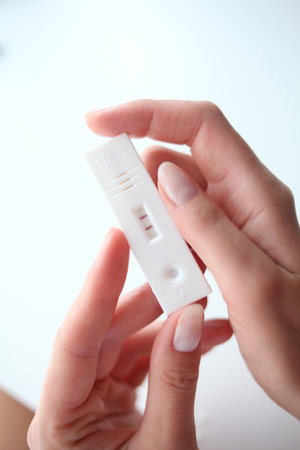 Female hand holding a positive pregnancy test on a white background, closeup