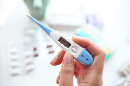 Female hand holding digital thermometer on blurred background, close-upの写真素材