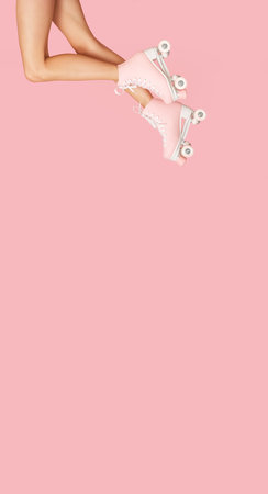 Cropped image of female legs in pink skates on pink backgroundの写真素材