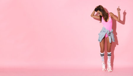 Full length portrait of a beautiful young woman on roller skates against pink backgroundの写真素材