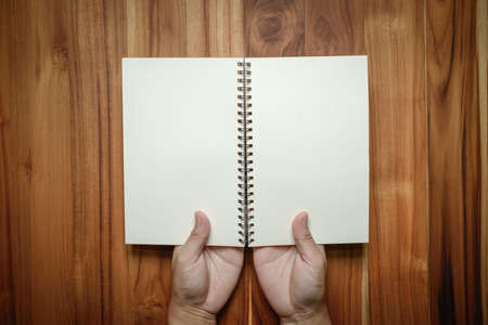 Hands holding notebook on wood background