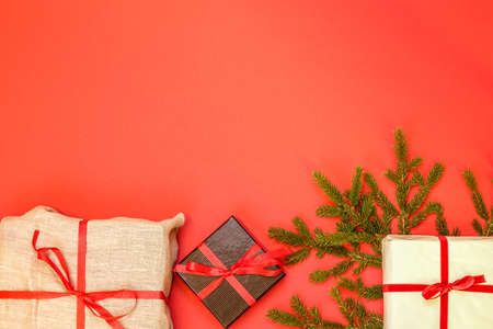Fir branch / twig and christmas gift boxes on red background. Burlap, white and black wrapping paper. Christmas border with empty blank copy space for text.の写真素材