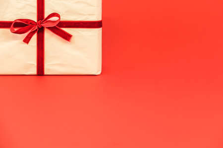 Christmas gift box on red background. White recycled / reused wrapping paper with red ribbon. Empty blank copy space for text.の写真素材