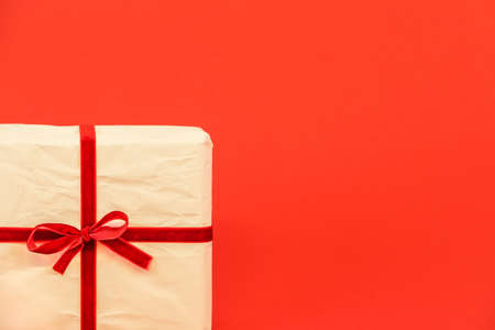 Christmas gift box on red background. White recycled / reused wrapping paper with red ribbon. Empty blank copy space for text.の写真素材