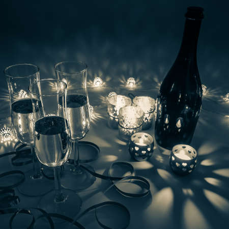 Cozy evening with glasses of champagne. For celebrations, special moments and new years eve. Warm decoration light, candles and bottle in background.の写真素材