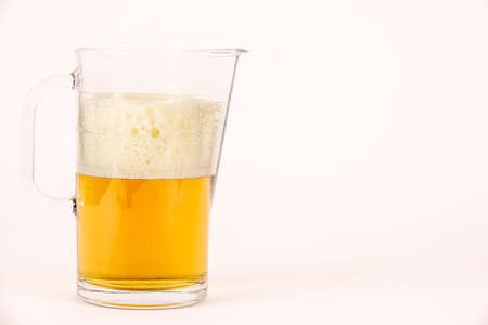 Pitcher of beer with foam on white background. Blank empty copy space for text.