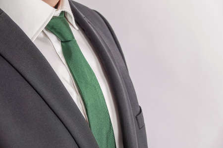 Close up of well dressed businessman in white shirt, green tie and black suit. White background with copy space for text.の写真素材