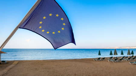 European Union EU flag with beach and sea in the background. Concept for traveling and tourism in Europe.の写真素材