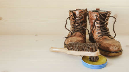 Shoe Care. A brush and a can of wax for polish and protection. A pair of brown old leather boots.の写真素材