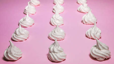 White meringues lined up on a pink background.の写真素材
