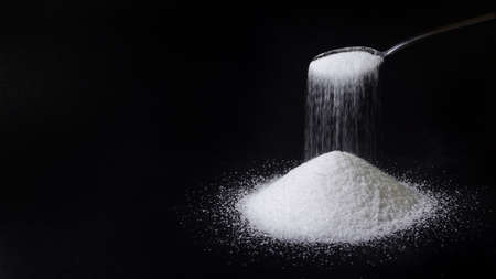 A tea spoon pours sugar in to a pile. Blank copy space for own text.の写真素材