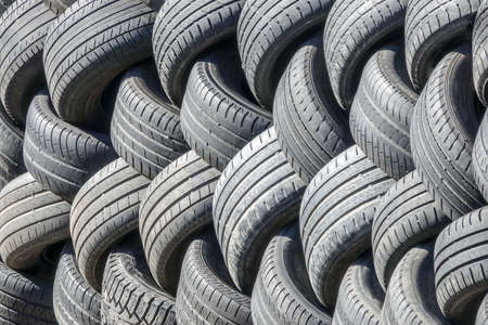 Old used tires that are lined up in a pile.