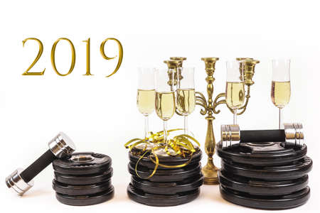 Glasses of champagne on weight plates and dumbbells. Concept for new years resolution 2019 and workout, exercise more next year.  - imageの写真素材