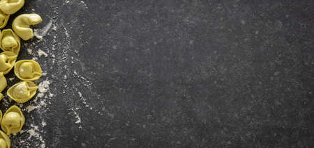 Homemade Italian traditional tortellini pasta. Dark stone background with copy space.の写真素材