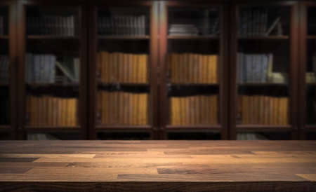 Blured bookshelf in small home library in the background. Table top for product display montage. Dark interior design.の写真素材