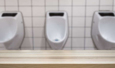 Wooden table top for product display montage. Blured urinal in the men's room in the background.