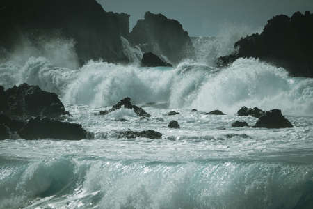 Waves crash along the black lava rock cliffs. Lanzarote, Canary Islands.の写真素材
