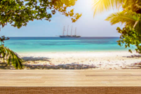 Sailboat in turquoise ocean with white beach and palm trees on tropical paradise island. Empty table top for product display montage background.の写真素材