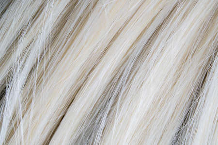 Close up of artificial blond wig hair. Synthetic hair texture background.