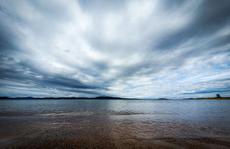 Dramatic sky over beautiful calm water in Gulf of Bothnia. Storsand, High Coast in northern Sweden.の写真素材
