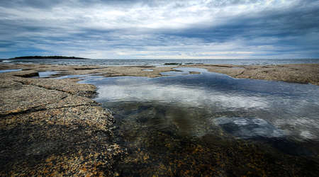 Dramatic sky Reflected in beautiful calm water in Gulf of Bothnia. Rotsidan, High Coast in northern Sweden.の写真素材