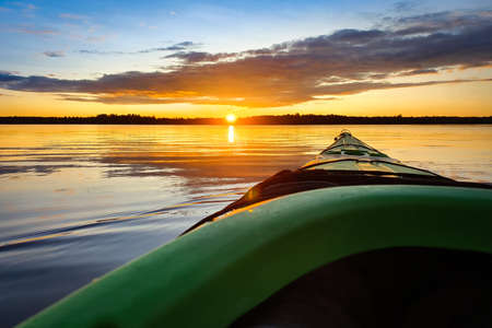 Paddling a sea kayak at sunset, calm water.の写真素材