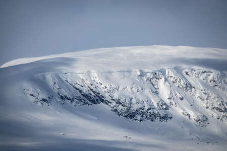 Winter landscape with dramatic cliff side on snowy mountain.の写真素材