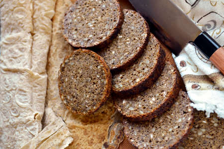 Slices of rye bread with a round shape next to the pita bread and knife.