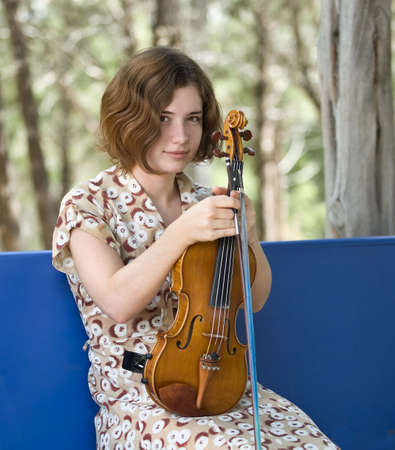 Pretty young woman or teenager taking a break from violin practiceの写真素材