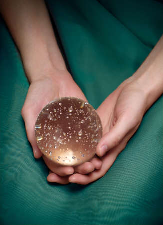 Woman's hands holding a crystal ball. Closeup, sparkly bubbles in the ballの写真素材