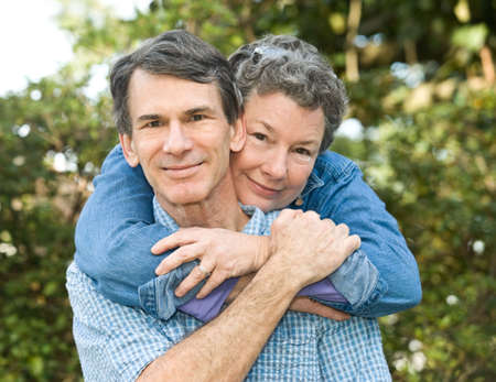 Happy mature couple hugging in a park-like setting, closeup, selective focus