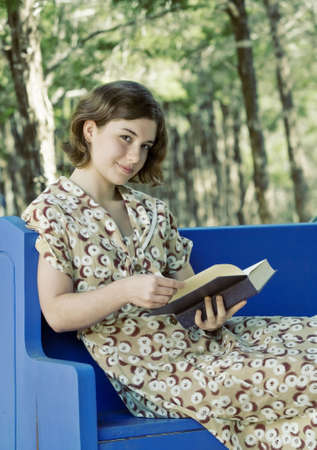 Pretty young woman/girl reading a book outdoors; soft focus portraitの写真素材