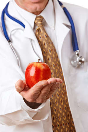 Doctor in white lab coat offering a bright red apple as a symbol of good nutritionの写真素材