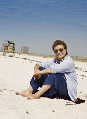 Mature woman relaxing on a sunny white sand beachの写真素材