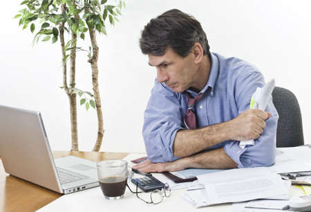 Stressed businessman at his office laptop, trying to find the best direction for his company.の写真素材