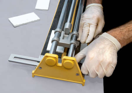 Closeup view of man's hands operating a tile cutter for cutting wall tiles.の写真素材