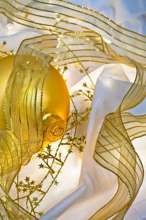 Glowing golden Christmas ornaments with translucent ribbons, sparkling gold stars and twinkling white lights. Short depth of field with glowing effects. Good for Christmas card or background.の写真素材