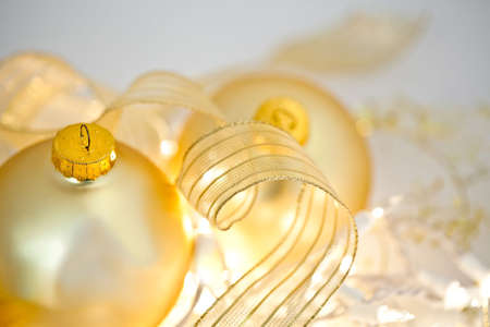 Glowing golden Christmas ornaments with transluscent ribbons, sparkling gold stars and twinkling white lights. Short depth of field with glowing effects. Good for Christmas card or background.の写真素材