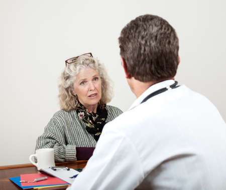 Pretty mature woman consults with her doctor in his office  Focus is on the womanâs face  の写真素材