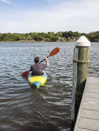 Back view of a man in a small kayak paddling out from the pier.の写真素材