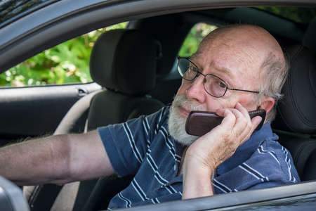 Closeup of elderly man in car calling for roadside assistance on cell phone  He looks hot and...