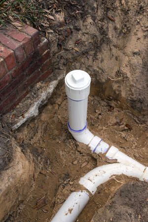 New PVC pipe sewer line and clean out installed in trench.の写真素材