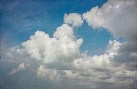 Blue sky with gathering cumulus clouds in shades of blue ranging from turqouise to cobalt blue, vintage light grunge texture. Good for backgrounds.の写真素材