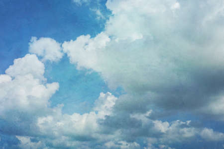 Blue sky with gathering cumulus clouds in shades of blue ranging from turqouise to cobalt blue, vintage light grunge texture. Good for backgrounds.の写真素材