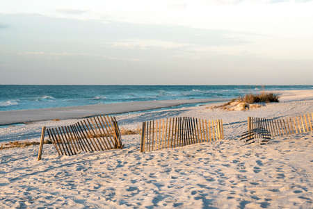 Sand fences and tide pools on Florida beach at low tide, early morning, warm light.の写真素材