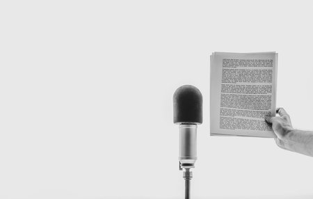 male hand holding a sheet of paper with text near microphoneの写真素材