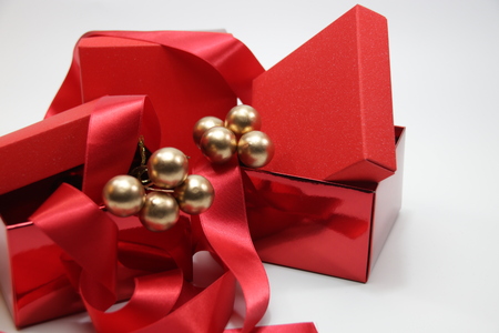 Red gift boxes with gold Christmas ornament and red ribbon on white backgroundの写真素材