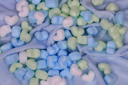 Blue and green heart shaped marshmallows on a blue background.