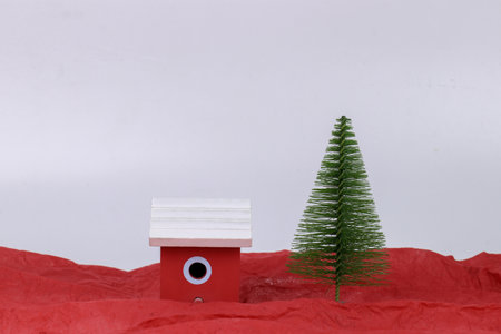 Small red bird house on a red background with a small Christmas tree.