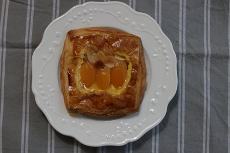 Apricot tart on a white plate on a striped tableclothの写真素材
